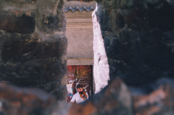 A photo of a violinist seen through a crack in a wall in Gamla Stan, Stockholm